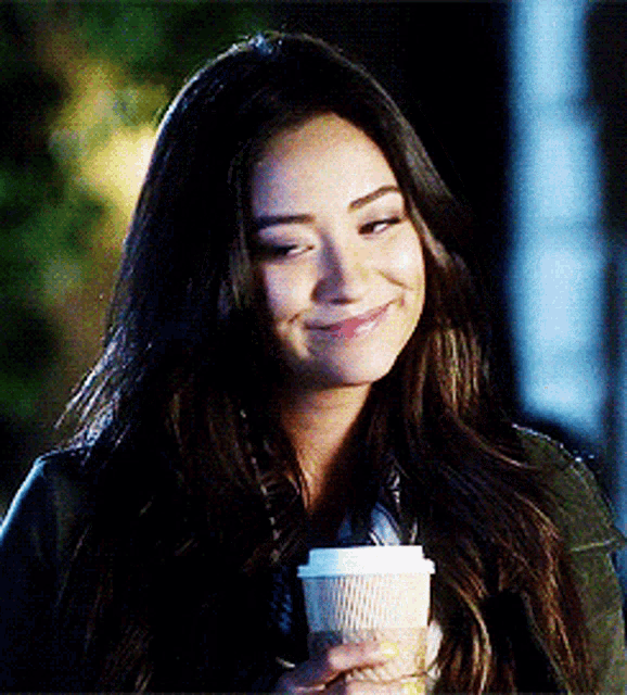 a woman holding a cup of coffee and smiling
