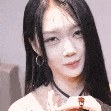 a woman with long black hair and a ring on her finger looks at the camera