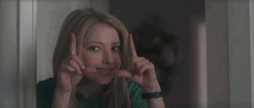 a woman is making a funny face while making a funny face with her hands .