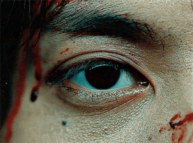 a close up of a person 's eye with blood on the face