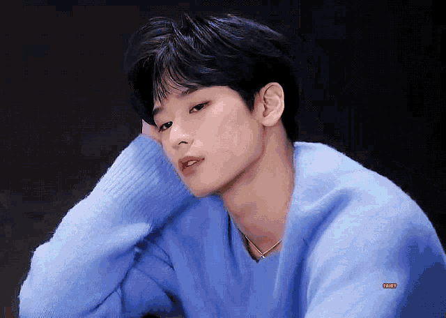 a close up of a person wearing a blue sweater with a yellow sticker that says ' hyun ' on the bottom