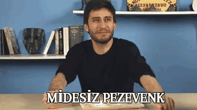 a man sitting at a table with a plate of food and the words " midesiz pezevenk " written on the table