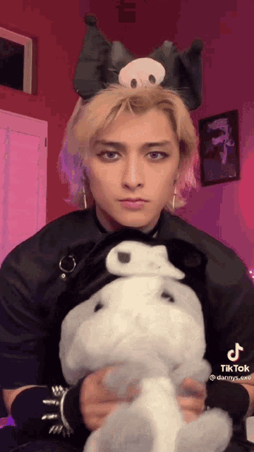 a man wearing a cat headband is holding a stuffed animal
