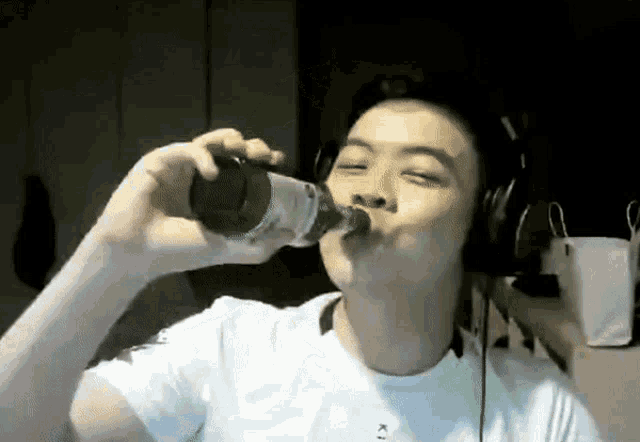 a man wearing headphones is drinking from a bottle that says k on it