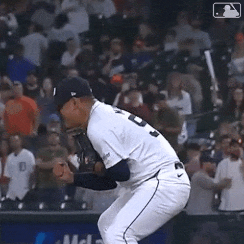 a baseball player is jumping in the air while holding a glove in front of a crowd .