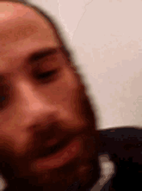 a close up of a man 's face with a beard making a funny face .