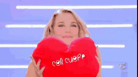 a woman is holding a red heart shaped pillow that says cuore