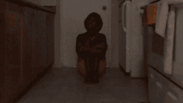 a person is sitting on the floor in a kitchen with their arms crossed