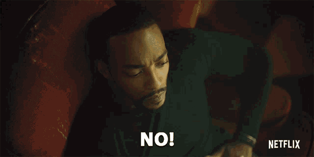 a man is laying on a red couch and says no in white letters