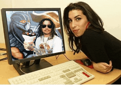 a woman sitting in front of a dell computer with a picture of a man on the screen