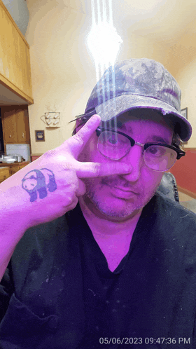 a man wearing glasses and a hat has a tattoo of a panda on his arm