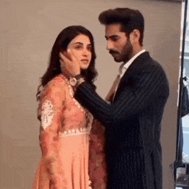 a man is touching the face of a woman in a pink dress .