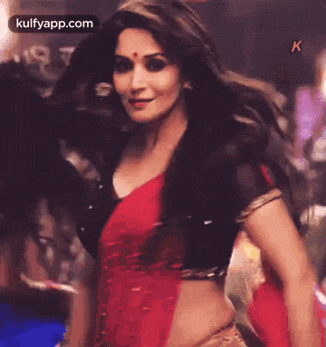 the woman is wearing a red and black saree and a black jacket .