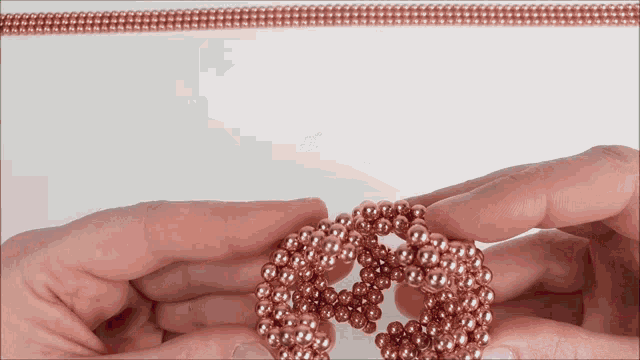 a person is holding a string of copper beads