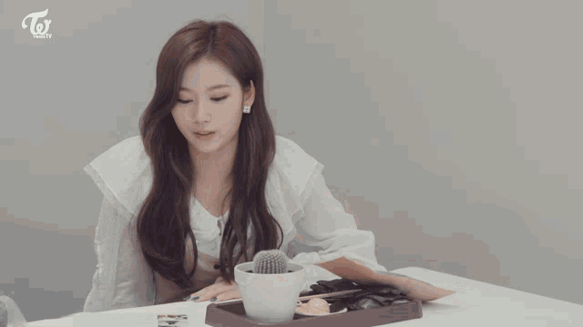 three women sit at a table with a tray of food and a twice logo on the wall