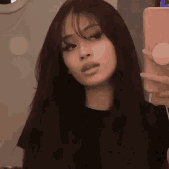 a girl with long hair is taking a selfie with her phone .