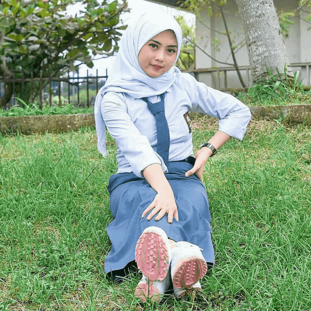 a girl in a school uniform sits in the grass