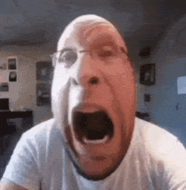 a man in a white shirt is making a funny face with his mouth open .