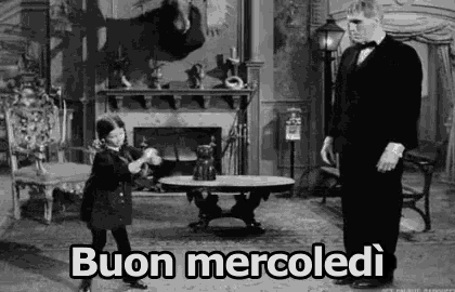 a black and white photo of a man in a tuxedo and a little girl in a living room .