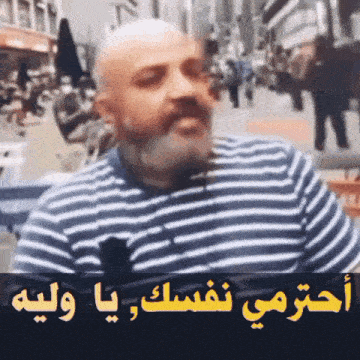 a man with a beard is wearing a striped shirt and talking to someone in arabic .