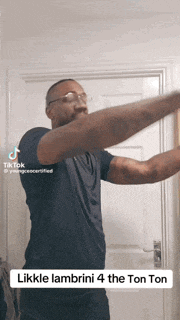 a man wearing glasses and a black shirt is standing in front of a door with his arms outstretched