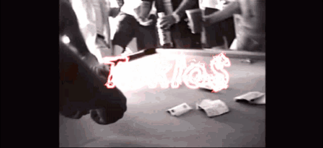 a group of people are gathered around a pool table and the word texas is lit up in red letters
