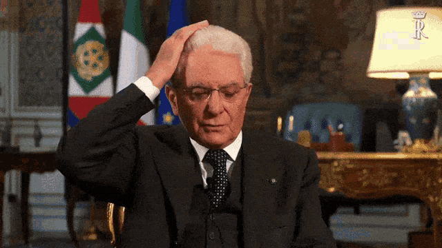 a man in a suit holds his hand to his head