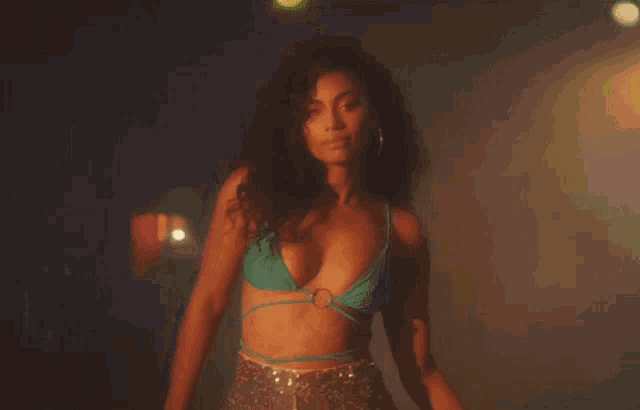 a woman in a green bikini top is standing in the dark
