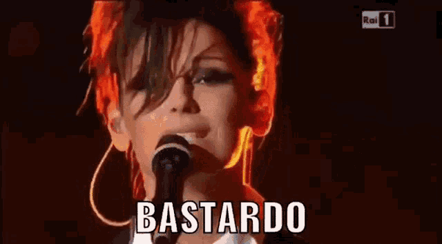 a woman singing into a microphone with the word bastardo on the screen