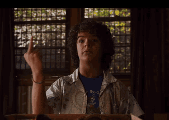 a young man with curly hair is wearing a shirt that says ' bug ' on it