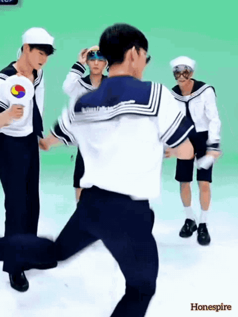a group of young men in sailor outfits are dancing in front of a green screen