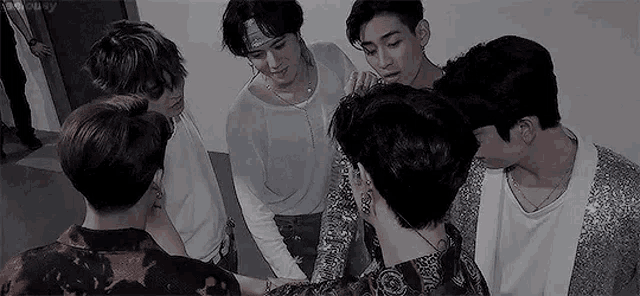 a group of young men are standing in a circle with their hands on each other .
