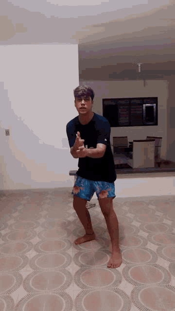 a man in a black shirt and blue shorts is standing on a tile floor