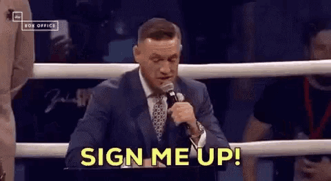 a man in a suit and tie is holding a microphone in a boxing ring and says sign me up .