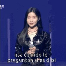 a woman in a black leather jacket is holding a microphone and says " asa cuando le preguntan sires disi "