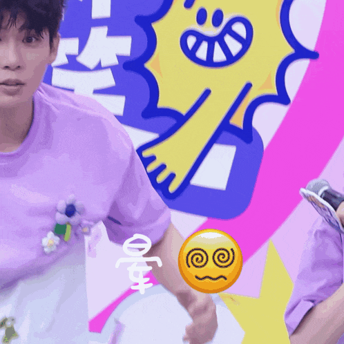 a man in a purple shirt is holding a microphone in front of a colorful background with a smiley face on it