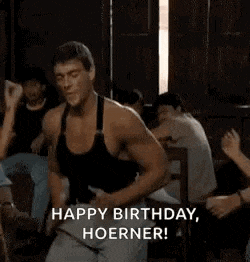 a man is dancing in a room with a group of people and says `` happy birthday , hoerner '' .