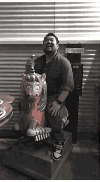 a man is sitting on a statue of a lion with a drink in his hand