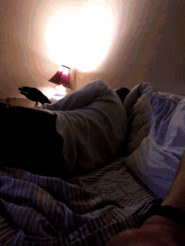 a person laying on top of a bed with a lamp on the wall