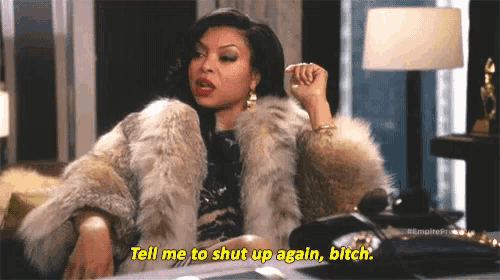 a woman in a fur coat is sitting on a couch and talking on a cell phone .