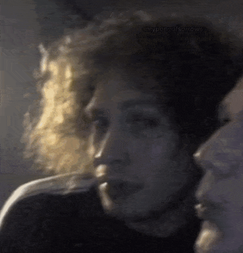 a close up of a person 's face with smoke coming out of their mouth in a dark room .