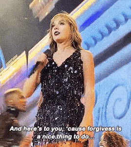 taylor swift is standing on a stage holding a microphone and speaking into it .