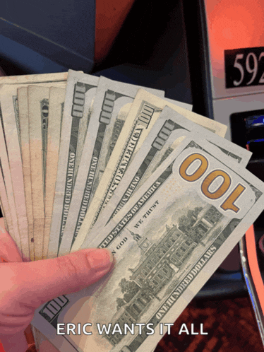 a hand holding a bunch of one hundred dollar bills with the caption eric wants it all