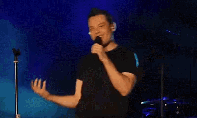 a man is singing into a microphone on a stage