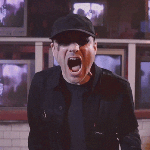 a man wearing a black hat and sunglasses is screaming with his mouth open