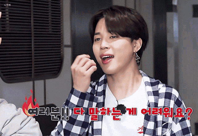 a young man wearing a plaid shirt and a white shirt with korean writing on it