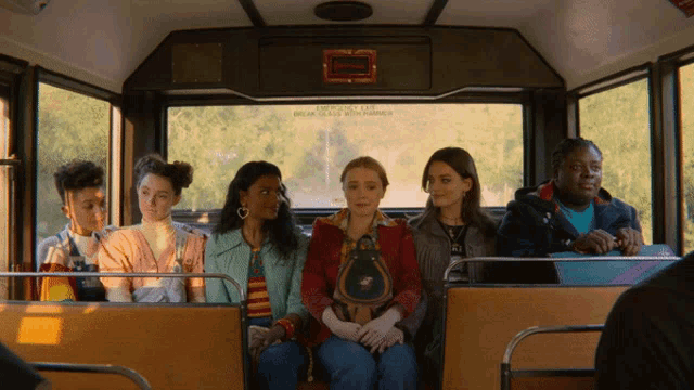 a group of people sitting on a bus with a sign above them that says " break glass with hammer "