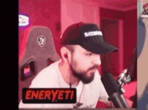 a man with a beard is sitting in front of a microphone in a room .