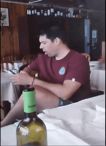 a man sitting at a table with a bottle of wine
