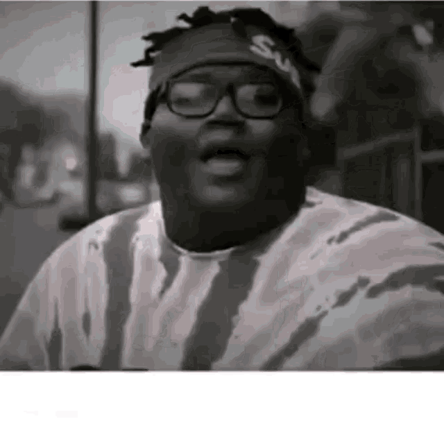 a man wearing glasses and a headband with the word supreme on it is making a funny face .